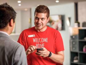 un hombre con una camisa roja mirando su celular en ibis Chesterfield North - Barlborough, en Chesterfield