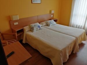 a bedroom with a bed and a desk and a bed at Pensión Teyma in Ponteceso
