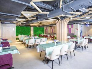 um restaurante com mesas e cadeiras e uma parede verde em Lavande hotel Jiande Xin'an jiang em Jiande