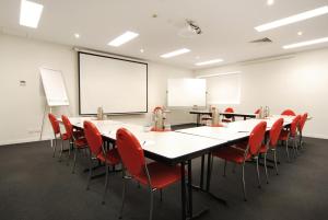 una sala de conferencias con una mesa larga y sillas rojas en Adara Hotel Richmond, en Melbourne