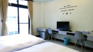 1 dormitorio con 1 cama y escritorio con TV en 花蓮站全民宿-無人民宿自助入住-包棟可烤肉可麻將, en Hualien City