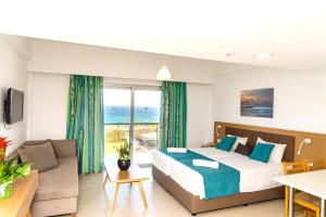 una camera da letto con un letto e un soggiorno di Helios Bay Hotel and Suites a Paphos