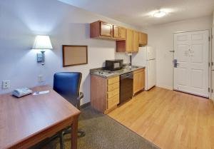 a small kitchen with a wooden table and a desk and a table and a refrigerator at Candlewood Suites Rockford, an IHG Hotel in Rockford