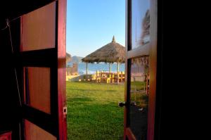 an open door with a view of a beach and an umbrella at Villas El Rancho Green Resort in Mazatlán