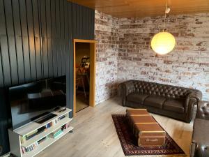 a living room with a leather couch and a tv at Ferienwohnung Esenshamm in Nordenham