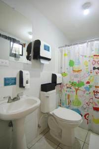 a bathroom with a toilet and a sink and a shower curtain at La Bicicleta Hostal in Managua