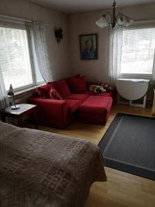 a living room with a red couch and a bath tub at Kouvola Guest house in Kouvola