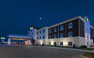 un edificio de hotel con una gasolinera por la noche en Holiday Inn Express and Suites Killeen-Fort Hood Area, an IHG Hotel, en Killeen