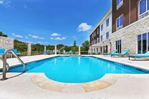 uma piscina com cadeiras azuis ao lado de um edifício em Holiday Inn Express and Suites Killeen-Fort Hood Area, an IHG Hotel em Killeen