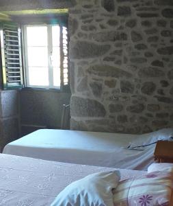 a bedroom with a bed and a stone wall at CASA CONCHA in A Estrada