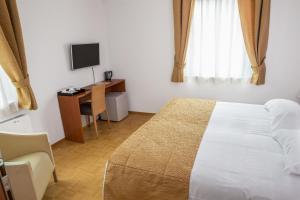 a bedroom with a bed and a desk and a television at Guest Accommodation Primula in Nova Gorica