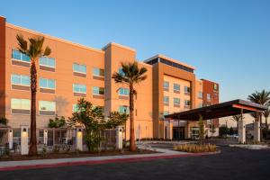 an orange building with palm trees in front of it at Holiday Inn Express & Suites - Moreno Valley - Riverside, an IHG Hotel in Moreno Valley