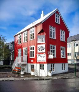 a red building with white trim on a street at House of the Snowbird in Reykjavík