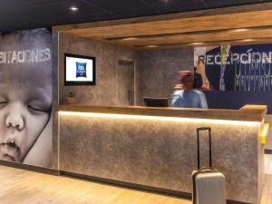 a hotel lobby with a waiting area with a suitcase at Ibis Budget Valencia Aeropuerto in Manises