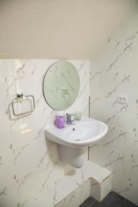 Ridon Lux Hotel في طشقند: حمام أبيض مع حوض ومرآة