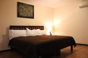ein Schlafzimmer mit einem Bett mit einer schwarzen Decke und weißen Kissen in der Unterkunft Hotel El Cafetalero in Xicotepec de Juárez