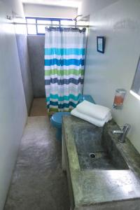 a bathroom with a sink and a toilet with a shower curtain at Todos Santos Hostel super fast and stable satellite wifi in Todos Santos