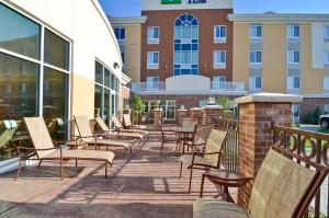 eine Reihe von Stühlen und Tischen auf einer Terrasse mit einem Gebäude in der Unterkunft Holiday Inn Express & Suites - Williston, an IHG Hotel in Williston