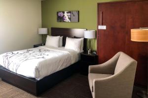 a hotel room with a bed and a chair at Sleep Inn & Suites Quebec City East in Boischâtel