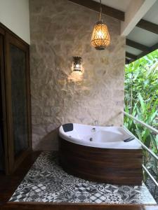 uma banheira na casa de banho com uma parede de pedra em Boutique Hotel y Spa Tangara Azul em Ojochal