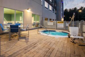 eine Terrasse mit einem Tisch, Stühlen und einem Pool in der Unterkunft Holiday Inn Express Queensbury-Lake George Area, an IHG Hotel in Queensbury