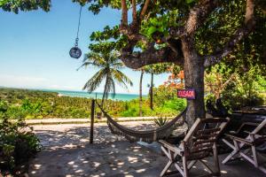 a hammock hanging from a tree with a view of the ocean at Pousada Anacã in Arraial d'Ajuda