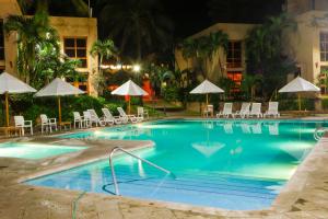 a swimming pool at night with chairs and umbrellas at Villas El Rancho Green Resort in Mazatlán