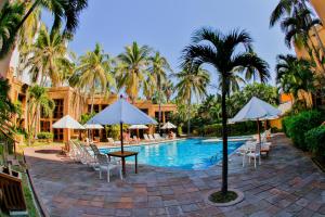 a resort pool with chairs and umbrellas and palm trees at Villas El Rancho Green Resort in Mazatlán