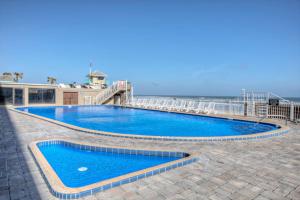 a swimming pool on a patio next to the ocean at Pirates Cove Condo Unit #704 in Daytona Beach Shores +29 photos