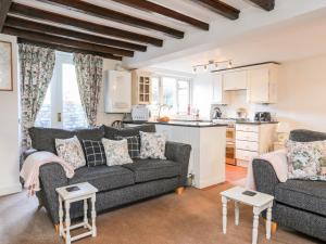 a living room with a couch and a kitchen at Y Bwthyn in Criccieth