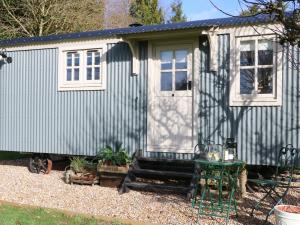 une petite maison avec une terrasse couverte et une table dans l'établissement Gibson's Hut, à Preston Candover