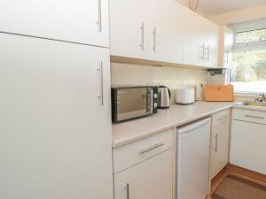 eine Küche mit weißen Schränken und einer Mikrowelle in der Unterkunft 304 Norton Park in Dartmouth