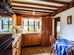 uma cozinha com armários de madeira e uma mesa com uma toalha de mesa azul em The Granary em Norwich