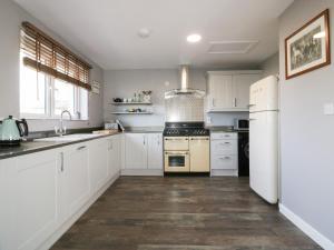 a kitchen with white cabinets and a refrigerator at Bonnie Cottage in Tintagel