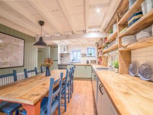 a kitchen with a long wooden table and blue chairs at Bwthyn Dyfi in Machynlleth