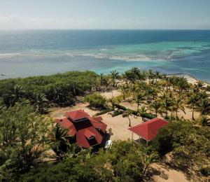 a resort with red umbrellas on a beach with the ocean at Sea Eye Hotel - Sunset Building in Utila