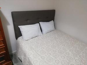 Una cama con dos almohadas blancas encima. en Monsalve10, en Zamora