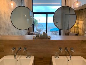 two sinks in a bathroom with two mirrors at Playa Grande by Tropical - Adults Only in Gavà