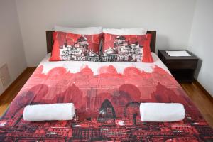 ein Bett mit einer roten Bettdecke und zwei Kissen in der Unterkunft Apartment Tino in Zagreb