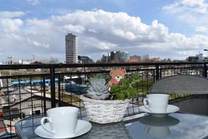 ein Tisch mit zwei Tassen und einer Topfpflanze auf einem Balkon in der Unterkunft Apartment Tino in Zagreb