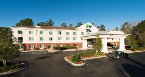 a large white building with a car parked in a parking lot at Holiday Inn Express & Suites Walterboro by IHG in Walterboro