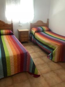 2 letti in una camera con coperte colorate di Casas Juani- chalet con piscina a Conil de la Frontera
