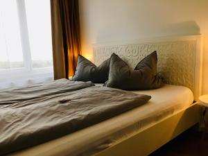 a bed with three pillows on it with a window at Ferienwohnung zu Weimar in Weimar