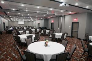 スーフォールズにあるHoliday Inn & Suites Sioux Falls - Airport, an IHG Hotelの白いテーブルと椅子が備わる宴会場