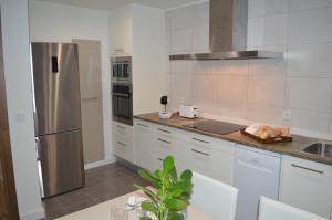 a kitchen with white cabinets and a stainless steel refrigerator at Casa Del Carmen II - Parking incluido in Tudela
