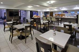 una sala da pranzo con tavoli e sedie in un ristorante di Holiday Inn Express and Suites Houston North - IAH Area, an IHG Hotel a Houston