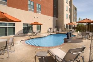 Holiday Inn Express & Suites San Antonio North-Windcrest, an IHG Hotel في سان انطونيو: مسبح مع كراسي وطاولات ومظلات