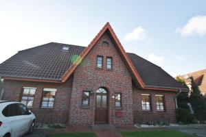 a red brick house with a black roof at Dünenrose in Horumersiel +5 photos