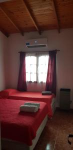 1 dormitorio con 2 camas con sábanas rojas y ventana en Departamentos Amoblados Nqn en Neuquén