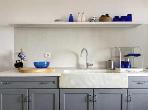 a kitchen with a sink and blue dishes on a shelf at Beach House in Zagora